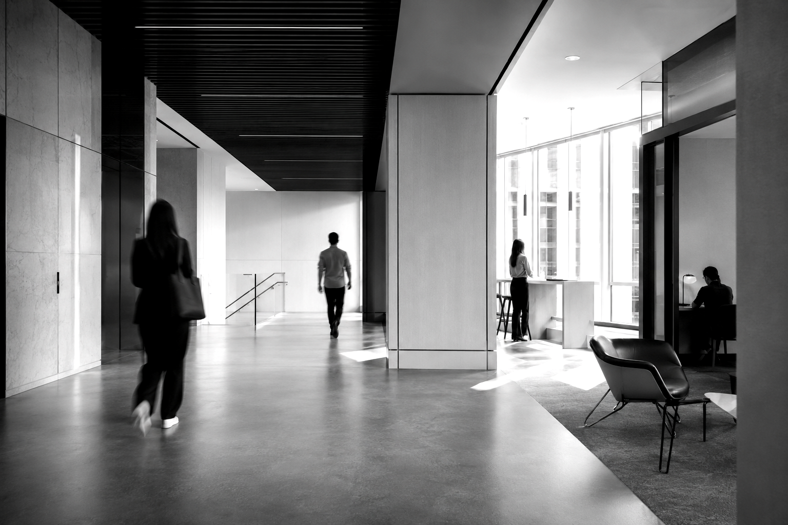 Motion-blurred figures moving through a modern office lobby